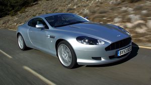 Превью обои aston martin, db9, 2004, серебряный металлик, вид сбоку, стиль, авто, астон мартин, скорость, природа, деревья, асфальт