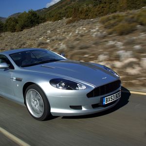 Превью обои aston martin, db9, 2004, серебряный металлик, вид сбоку, стиль, авто, астон мартин, скорость, природа, деревья, асфальт