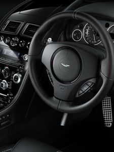 Превью обои aston martin, db9, 2010, черный, салон, интерьер, руль, спидометр