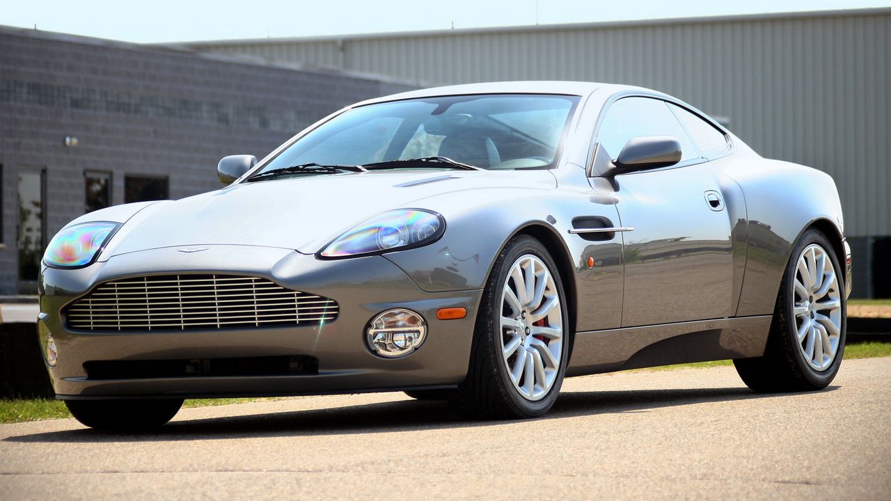 Обои aston martin, v12, vanquish, 2001, серый, вид сбоку, стиль, астон мартин, здание