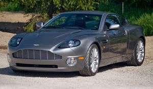 Превью обои aston martin, v12, vanquish, 2001, серый, вид спереди, астон мартин, трава