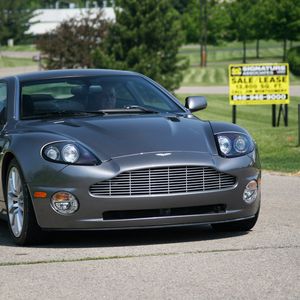 Превью обои aston martin, v12, vanquish, 2001, серый, вид спереди, астон мартин, деревья