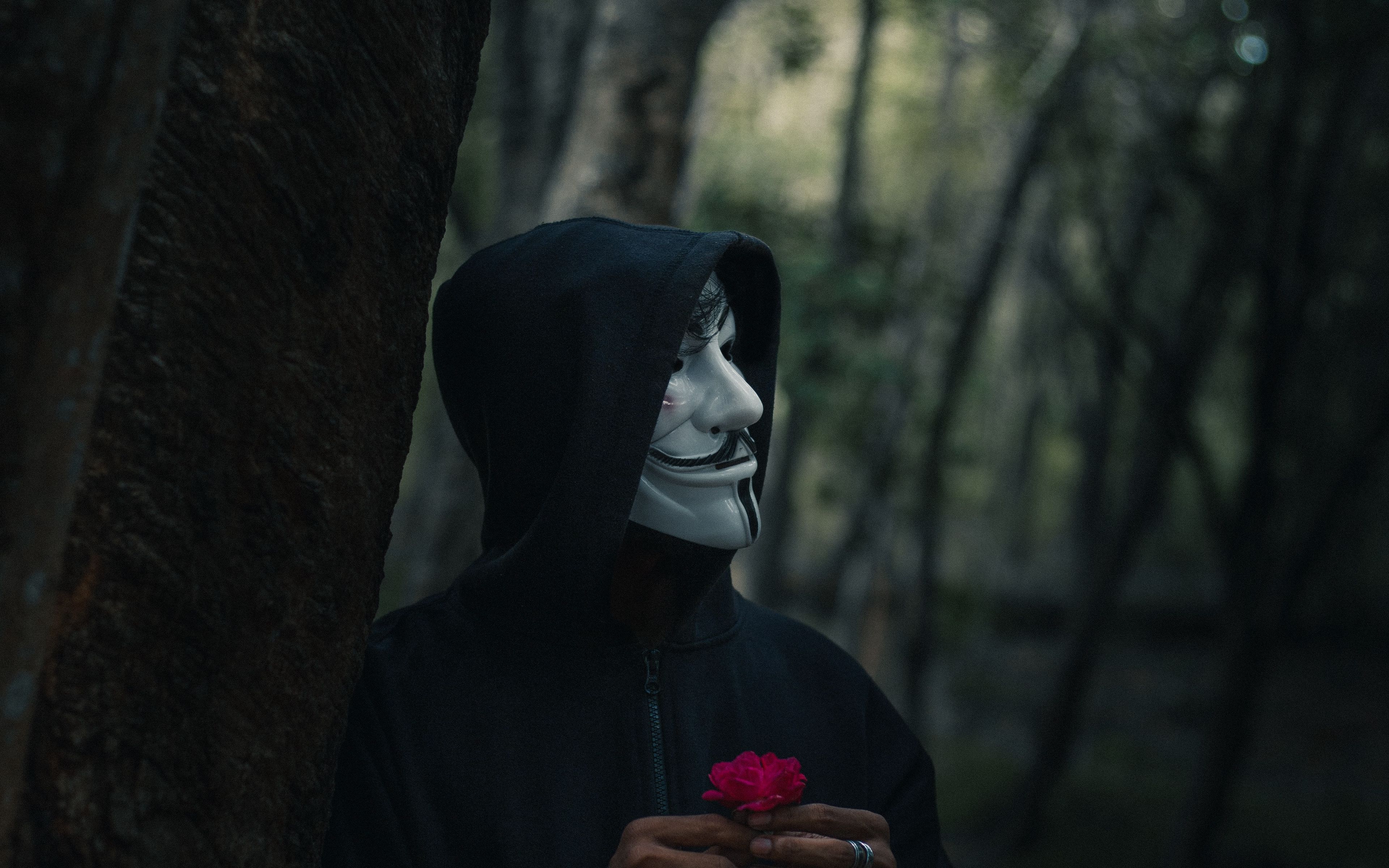 Человек в маске Анонимуса в капюшоне