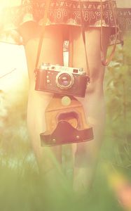 Превью обои девушка, фотоаппарат, солнце, трава, ноги, платье, блик
