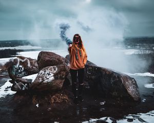 Превью обои девушка, маска, дым, дымовая шашка, камни