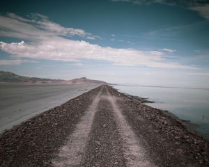 Превью обои дорога, побережье, камни, вода, холмы, облака