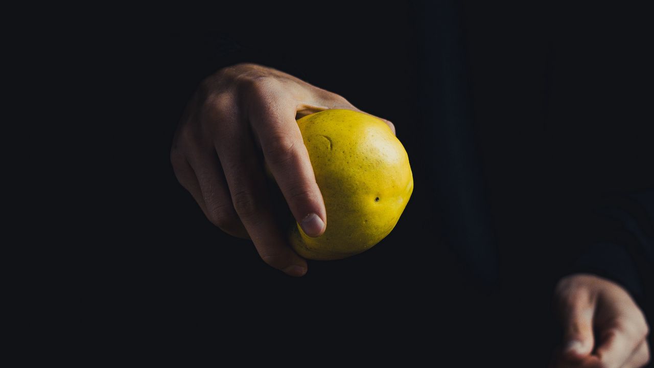 Обои яблоко, рука, фрукт, темный фон