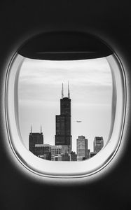 Превью обои иллюминатор, чб, окно самолета, здания, полет