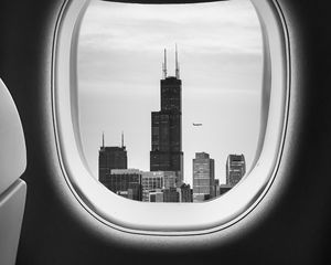Превью обои иллюминатор, чб, окно самолета, здания, полет