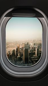 Превью обои иллюминатор, город, небоскребы, вид сверху, окно