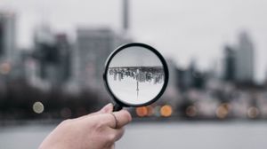 Превью обои лупа, рука, город, размытость, фокус