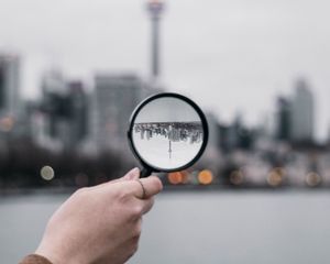 Превью обои лупа, рука, город, размытость, фокус