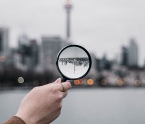 Превью обои лупа, рука, город, размытость, фокус