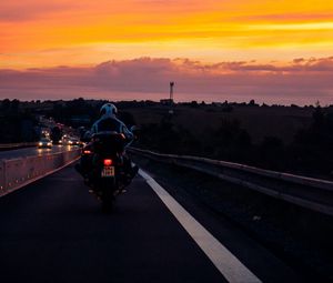 Превью обои мотоциклист, закат, небо, облака, дорога, разметка