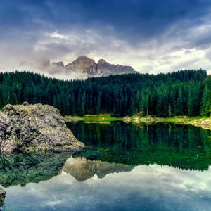 Превью обои озеро, камень, глыба, середина, водная поверхность, горы, лес, хвойный