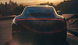 Превью обои porsche, спорткар, вид сзади, черный, солнечный свет, движение