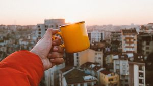 Превью обои рука, кружка, город, крыши, рассвет, восходящее солнце