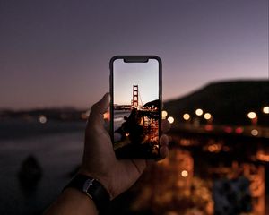 Превью обои рука, телефон, фото, мост, закат, огни