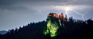 Превью обои скала, дом, свет, молния, сумерки