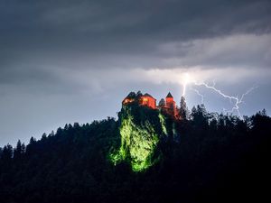 Превью обои скала, дом, свет, молния, сумерки