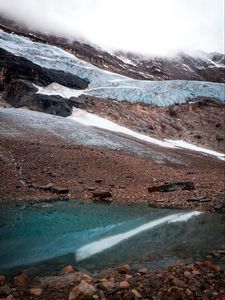 Превью обои склон, скала, снег, галька, вода