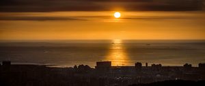 Превью обои солнце, закат, побережье, море, город, темный