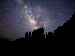 Превью обои туманность, звездное небо, скалы, звезды, силуэт