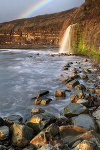 Превью обои водопад, камни, море, скалы, радуга, природа